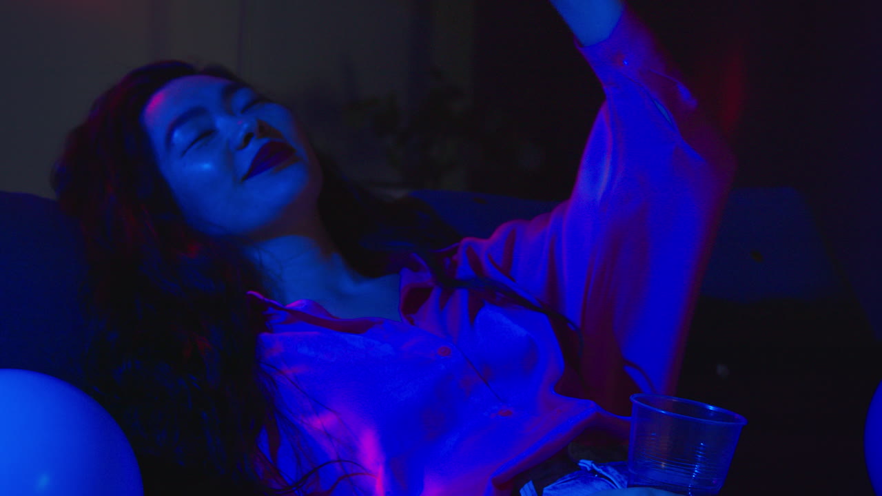 mujer borracha tendida en el sofá bebiendo alcohol en la fiesta de la casa