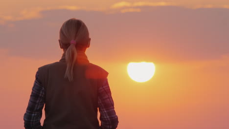 Eine-Silhouette-Einer-Frau,-Die-Auf-Die-Große-Rote-Sonne-Zugeht