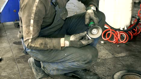 auto mechanic polish rusty bolts with electric grinder tool near lifted car