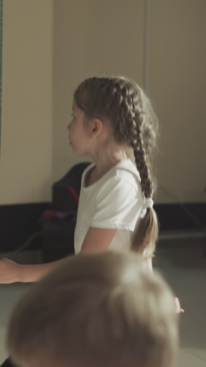 Child jumps near punching bag in gym. Little girl with braided hair exercises with fighting equipment in sports club slow motion. Children development