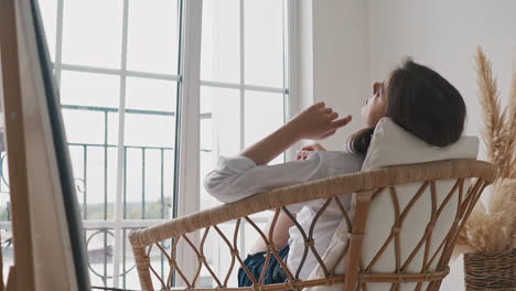 Tired-woman-rests-after-lesson-sitting-in-rattan-armchair