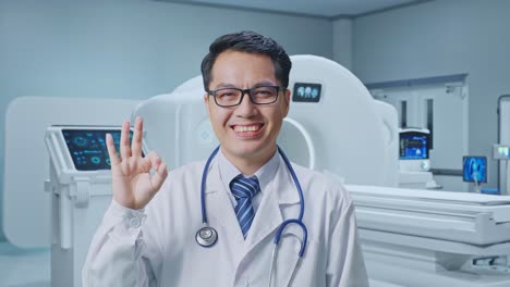 Close Up Of Asian Male Doctor Showing Okay Gesture And Smiling With MRI Machine In The Hospital