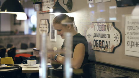 Lächelnde-Frau,-Die-Im-Café-Sitzt-Und-Eine-Nachricht-Auf-Ihrem-Smartphone-Tippt