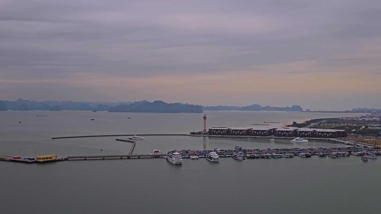 조용한 공중 관점은 하롱의 화려한 마리나와 그 상징적인  등대, 조용한 물속에 어져있는 선박, 그리고 흐릿한 카르스트 형성에 싸인 웅장한 마천루를 포착합니다.