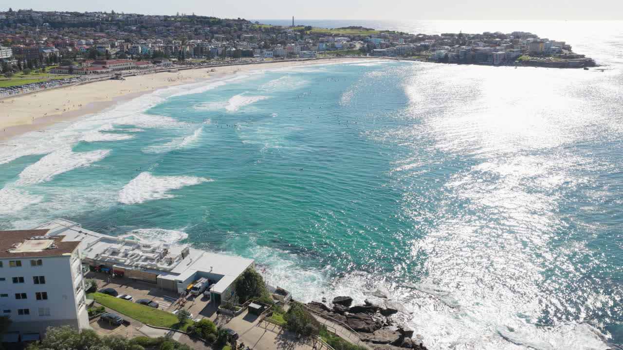Ampia veduta aerea di surfisti sulle onde bianche e sull'acqua turchese della famosa meta turistica e surfistica Bondi Beach a Sydney, in Australia, in una soleggiata giornata estiva