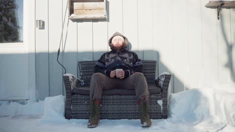 a man is seated on a couch, savoring a hot drink during the winter season - static shot