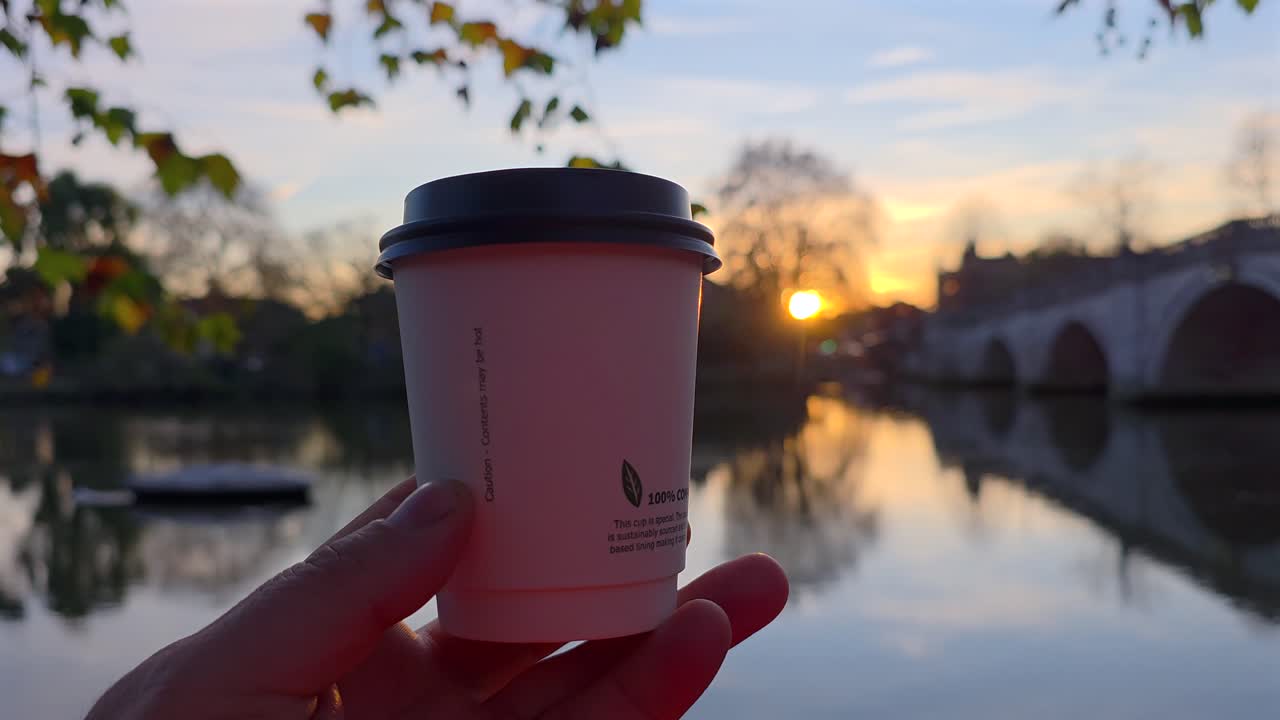 Tazza di caffè in mano con tramonto sul Richmond Bridge e fiume sullo sfondo
