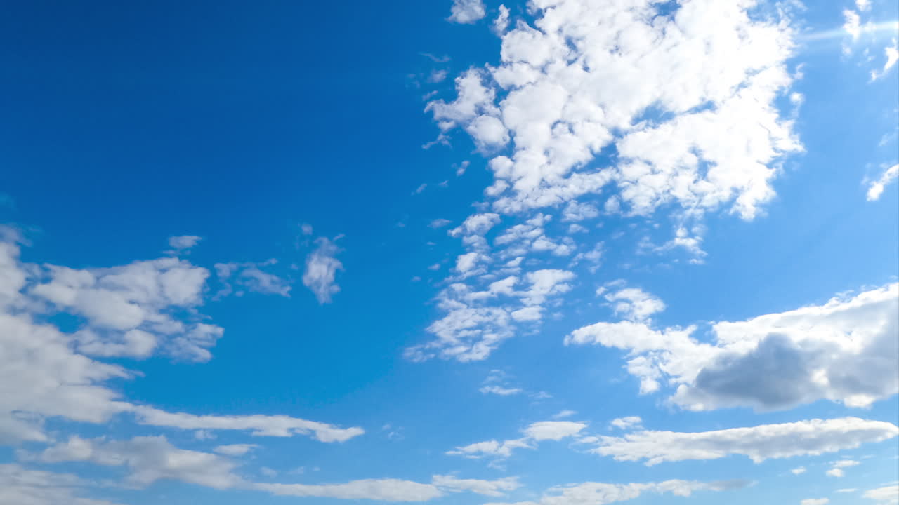 Quick transformation of white soft clouds in the atmosphere. Cumulus cloudscape moving with the wind from low angle perspective. Timelapse.