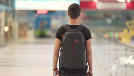 Joven-Con-Una-Mochila-Negra-Caminando-En-El-Centro-Comercial