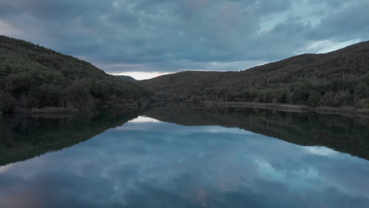 drone rápido sobre las aguas tranquilas del lago de montaña que reflejan las nubes de color atardecer