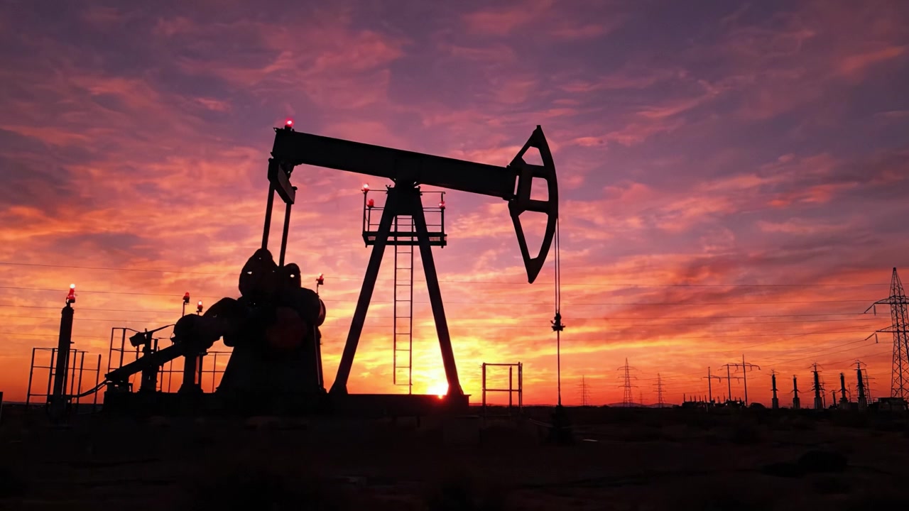 Dramatic Sunset Silhouette of an Oil Pump Jack Against a Colorful Sky Highlighting the Intersection of Nature and Industry