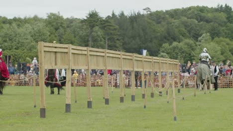 armoured knights riding their horses to warm up as they enter the arena during a medieval tournament joust at leeds castle, kent, england