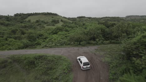 aerial following vehicle driving on dirt road in tropical mountains of colombia