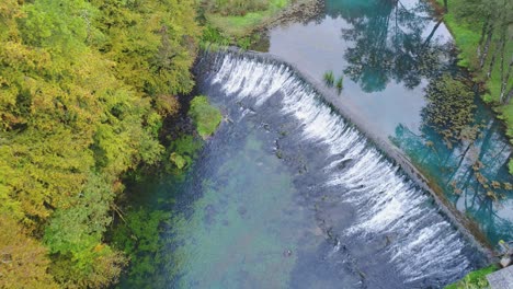 Fly-over-waterfalls-with-pristine-water-surrounded-by-lush-forest