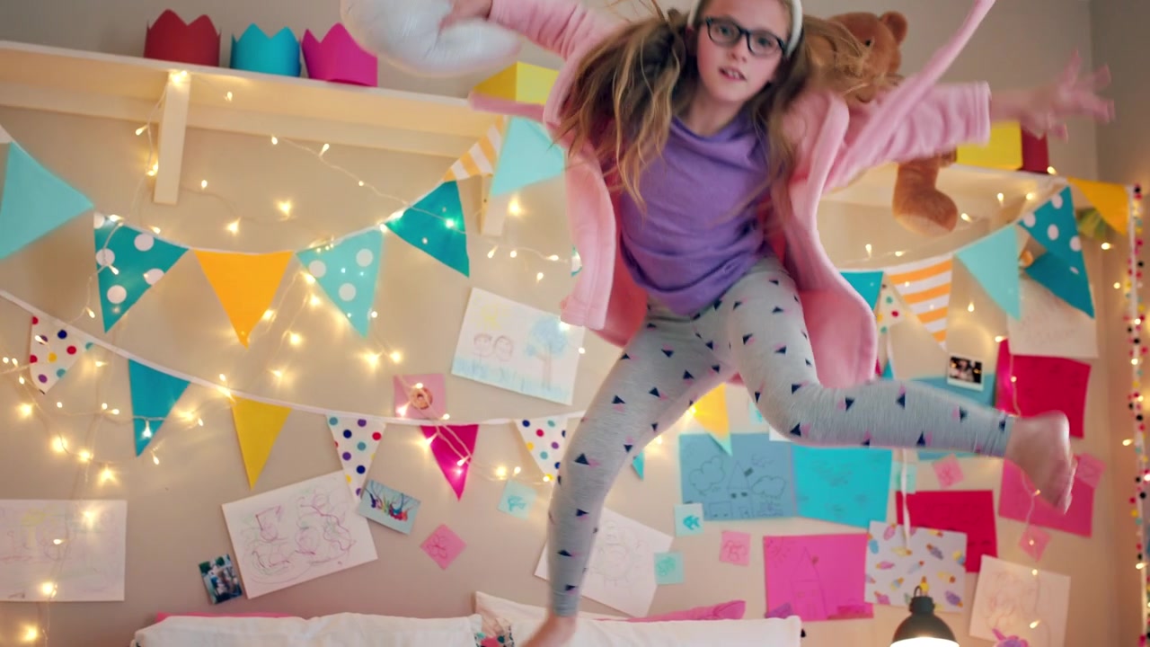 Young Girl Wearing Bunny Ears Jumping on Her Bed