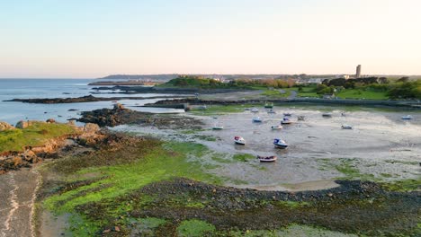 Eingang-Zum-Hafen-Von-Bordeaux,-Guernsey,-Tiefflug-Bei-Ebbe-Mit-Booten,-Die-Auf-Sandigem-Grund-Trocknen,-Und-Grünen-Algen-Am-Küstenvorland-Am-Hellen-Späten-Nachmittag