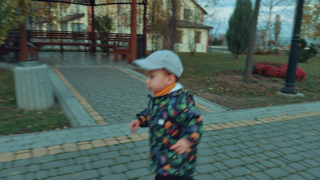 Lovely cute kid running by the alley in the park. Curious toddler looking around while running in autumn nature.