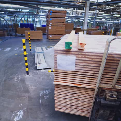 factory of laminate production. forklift truck taking a pile of wooden pallets. interior of warehouse of a parquet board production.