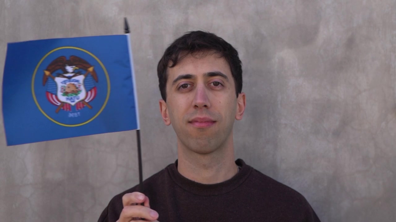 Uomo adulto che sventola la classica bandiera dello stato dello Utah. Rallentatore.