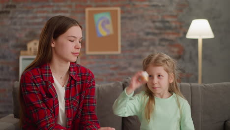 Girl-shakes-bottle-with-golden-paint-with-elder-sister