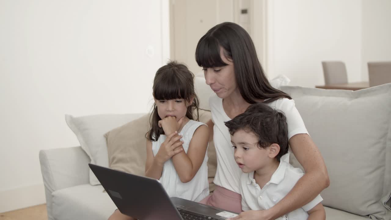 mamá feliz y dos niños lindos usando computadora portátil juntos
