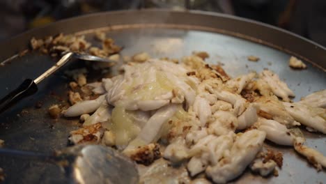 Close-up-of-pan-fried-squid-eggs-in-a-smoking-hot-large-frying-pan-at-a-hawker-center