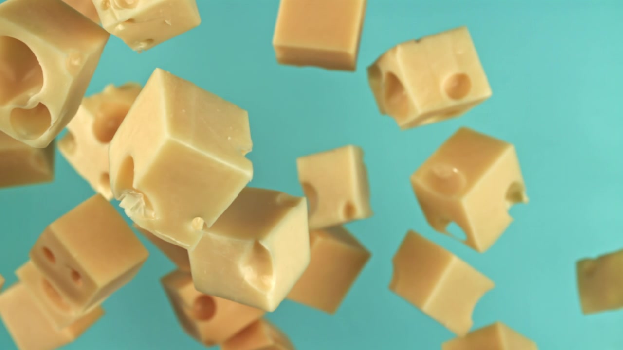 Cubes de fromage suisse tombant au ralenti sur fond bleu