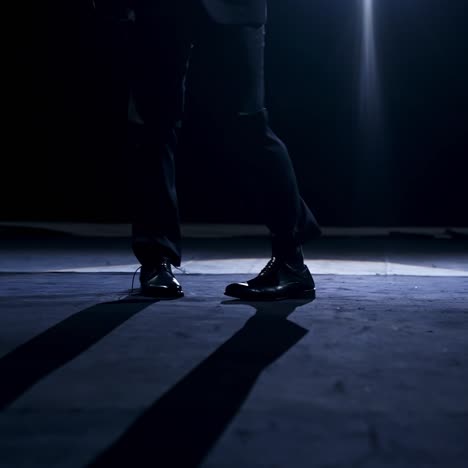 legs of a dancer in move. man in trousers and shoes dancing on the stage in dark scenic light
