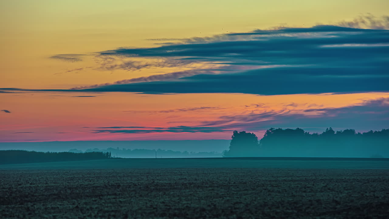 tiro de lapso de tiempo de nubes voladoras en el cielo durante el colorido amanecer de la mañana en los campos agrícolas