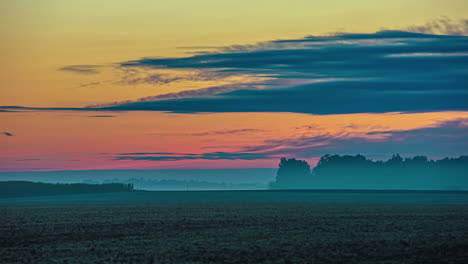 Time-lapse-shot-of-flying-clouds-at-sky-during-colorful-morning-sunrise-on-agricultural-fields