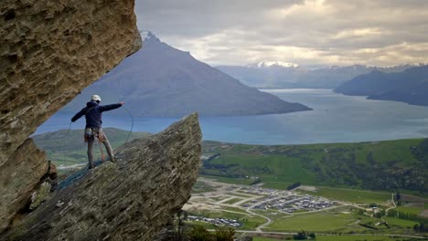 Mountain-Rock-Climber-Coiling-Seil-Auf-Einer-Klippe-Mit-Blick-Auf-Einen-Wunderschönen-See-Bei-Sonnenuntergang-An-Einem-Bewölkten-Tag