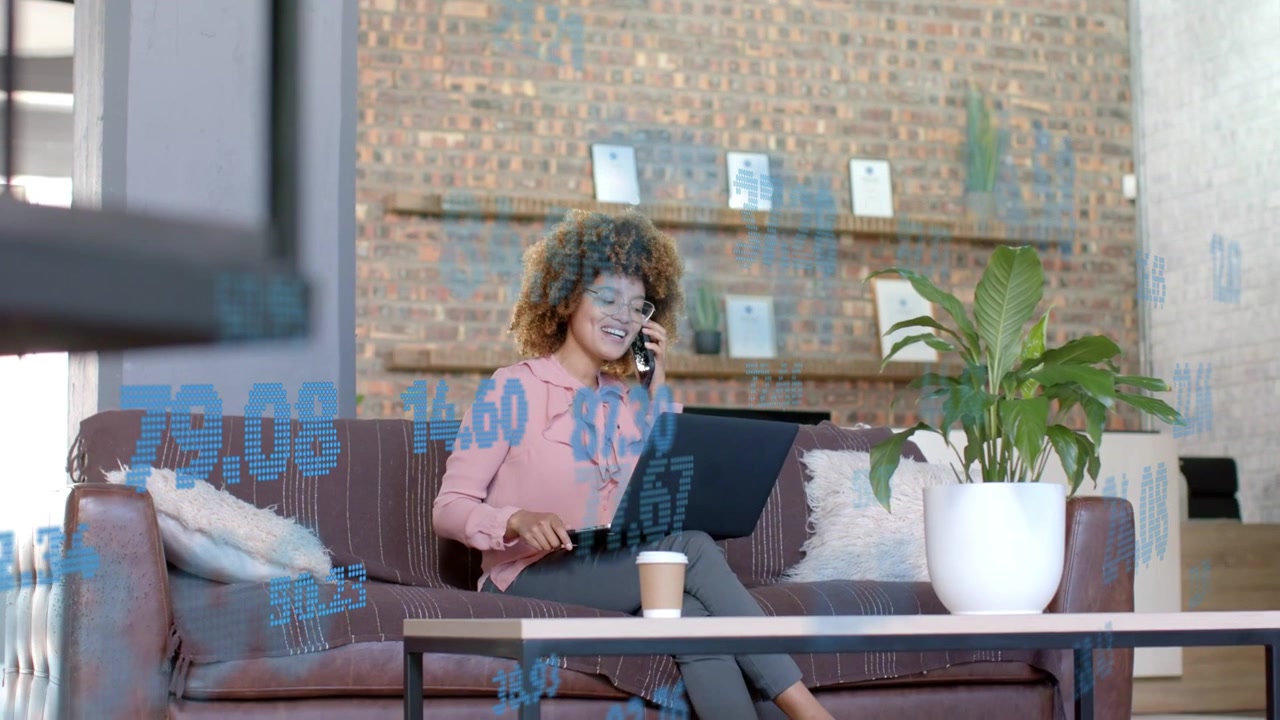 Businesswoman answering client call while reviewing data on laptop with blue overlays on laptop