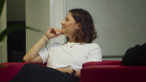 A-young-woman-sits-comfortably-in-a-chair-and-listens-to-someone-off-camera