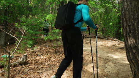 hombres excursionistas caminando por el sendero de la ladera del bosque en un soleado día de verano