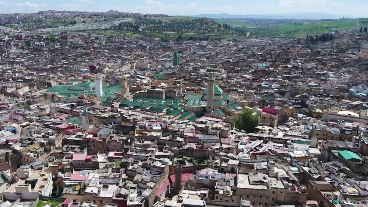 Expansive drone panorama of Fez El Bali medina. Captures the immense urban density, iconic mosque minarets, and the historic landscape of the world's oldest pedestrian city and university