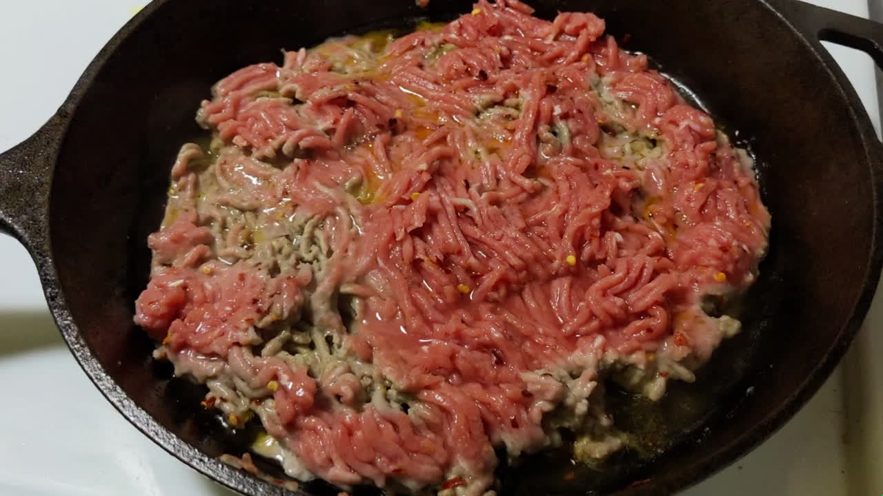 Over head. Timelapes. Frying ground beef on a cast iron skillet.