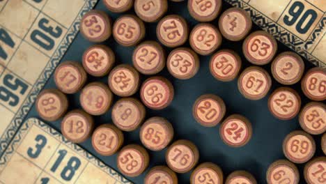 cinematic rotating smooth shot from above of a pile of bingo wooden barrels in a square, woody figures, old numbers background, vintage board game, professional lighting, 4k video