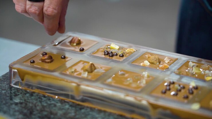 Adding nuts and fruits to chocolate bars in molds