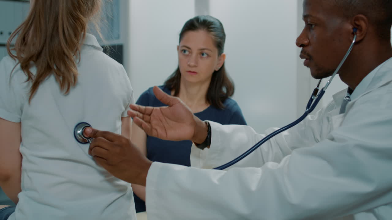 Doctor Examining Child with Stethoscope with Mother Present