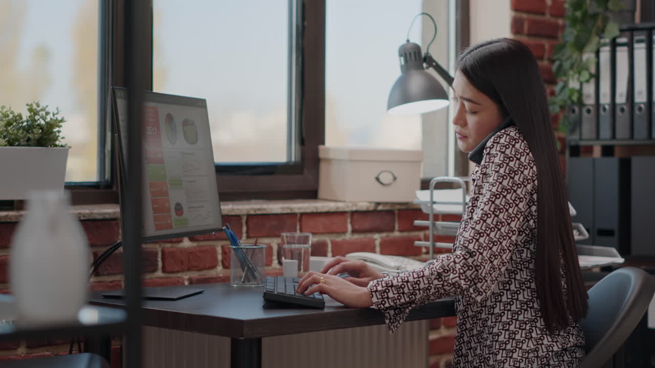 Asian woman talking on phone call while she works