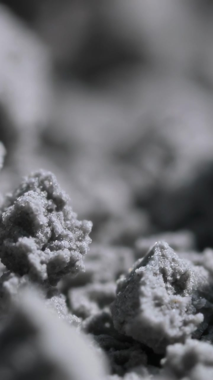 Video verticale: Telecamera macro con messa a fuoco che rivela una texture polverosa in granuli agglomerati in studio