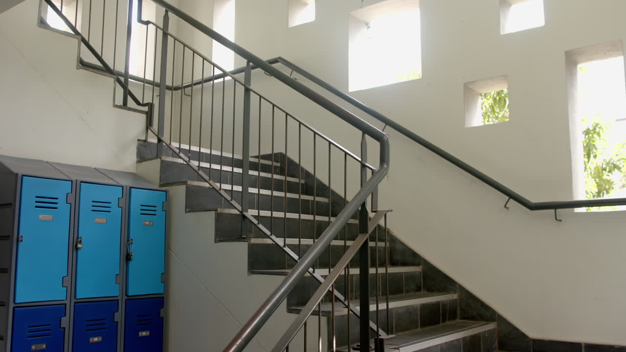 A staircase beside blue lockers in a bright high school corridor