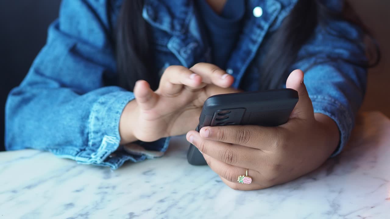 A person is using a smartphone while sitting at a table