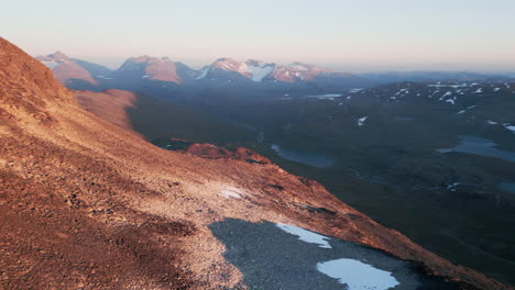 Aerial-view-drone-shot-of-a-mountainous,-barren,-lake-rich-landscape-on-a-sunny-day,-snow-on-the-mountain-tops,-outdoor,-wilderness