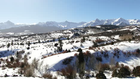 aerial cinematic drone mid winter of san juan mountain range ridgway telluride 14er stunning ranching farm land of colorado early morning mid winter blue sky pan to the right movement