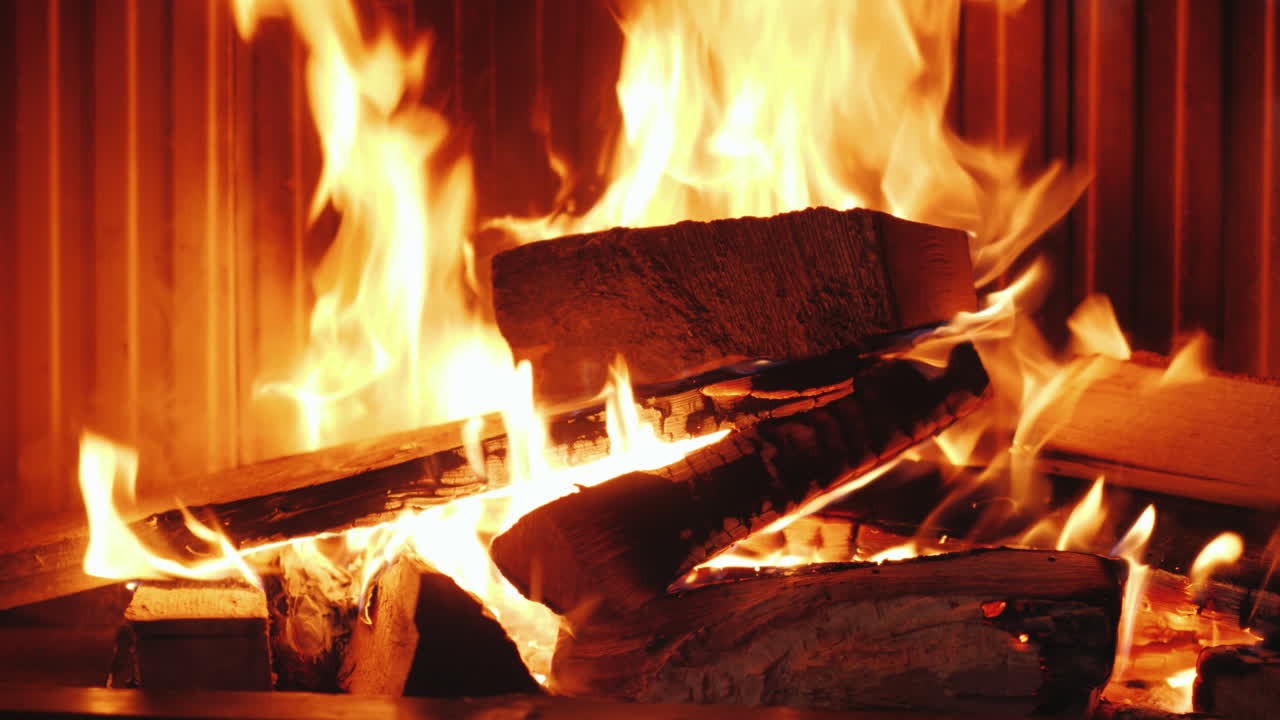 한 남자가 참나무 장작을 벽난로 삽입물에 넣고 유리 단두대 유형을 f에 넣습니다.