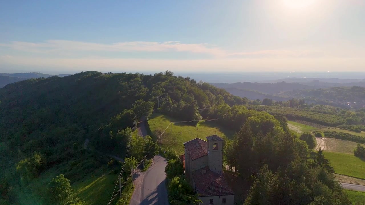 Un sorvolo di drone cattura una chiesa storica e rigogliosi vigneti sotto la brillante luce solare pomeridiana.