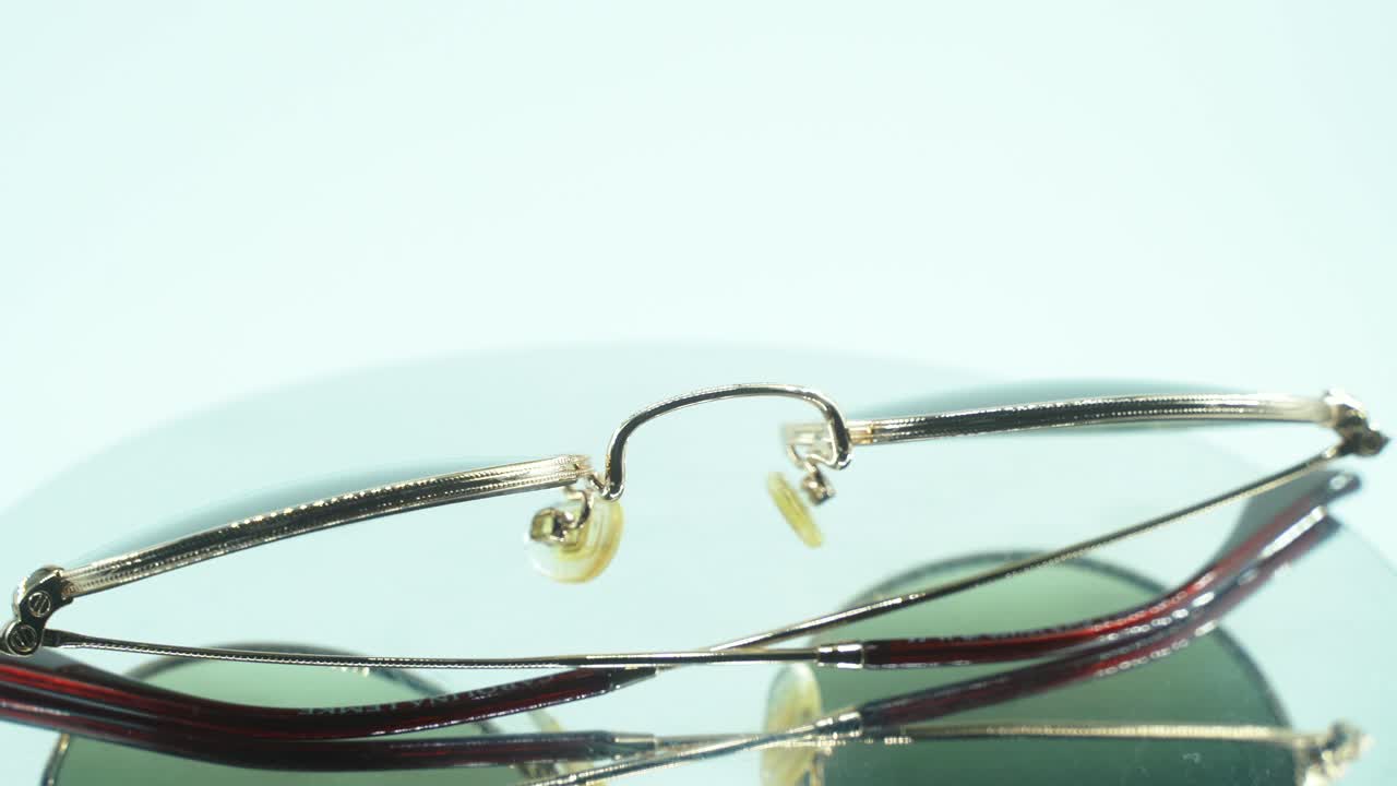 360도 회전 스탠드, 스튜디오 조명, 제품 4k 비디오, 슬로우 모션에 금색 선글라스를 놓는 클로즈업 샷