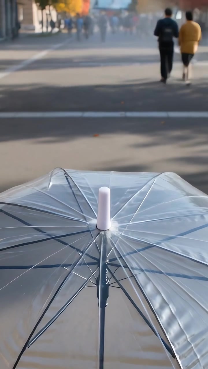 Video verticale: Una persona che tiene un ombrello trasparente, mantenendo l'inquadratura centrata mentre un uomo attraversa la piazza.