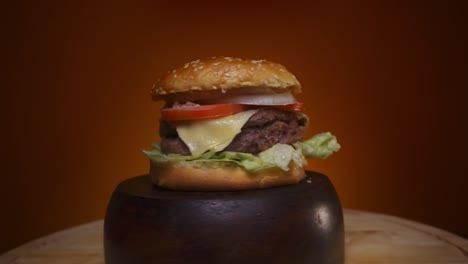 burger-rotating-on-a-wooden-base-with-orange-background